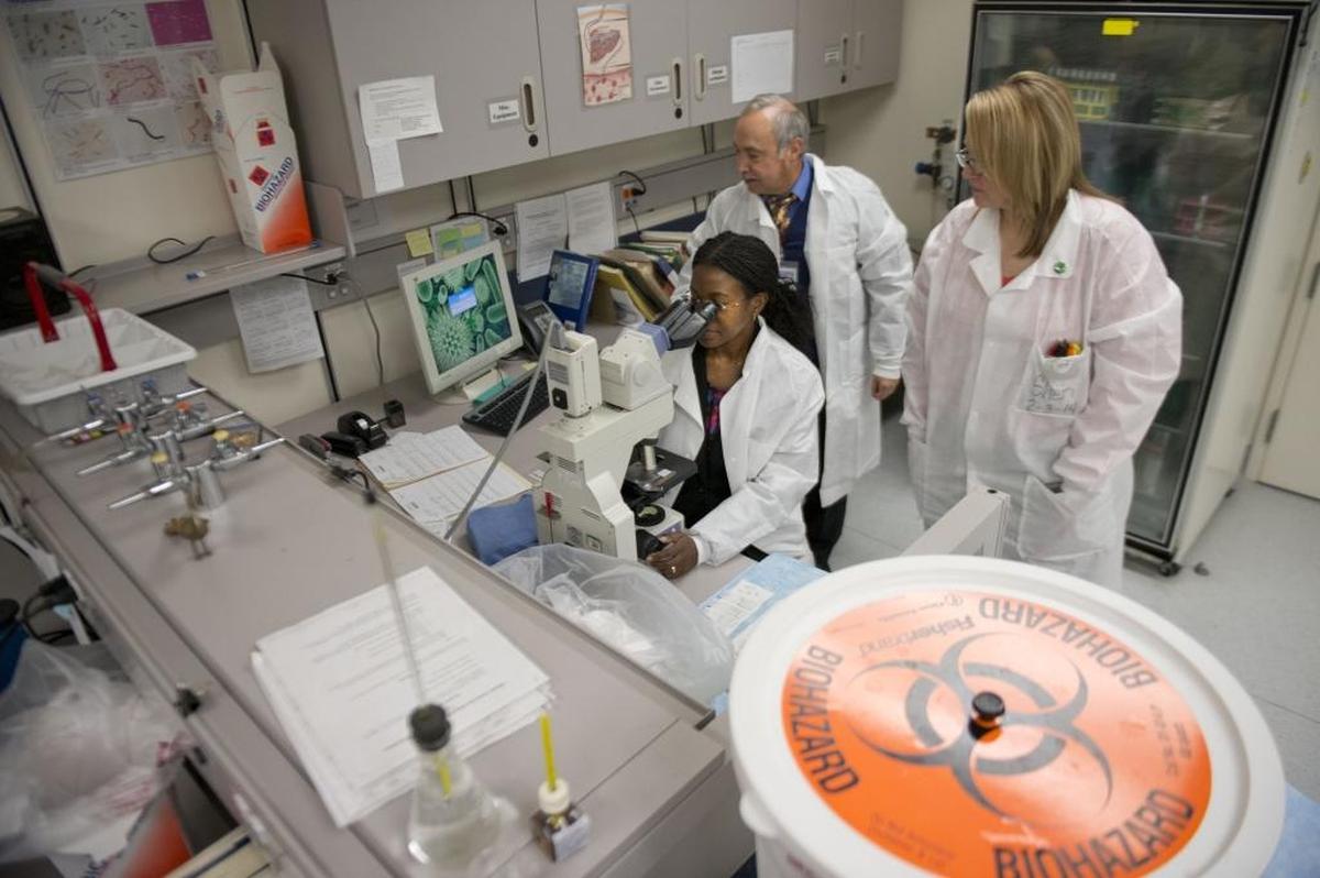 Dr. Olivia Kasirye, the Sacramento County Public Health Officer, looks at a specimen at the Sacramento County Public Health Laboratory with Dr. Anthony Gonzalez, Public Health Laboratory Director and Sheri Tomkins a Public Health Microbiologist on on Friday, Feb. 7, 2014.