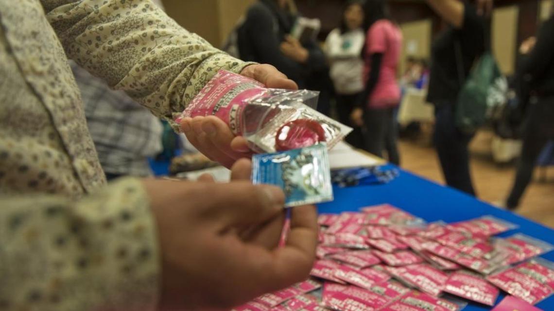 A health educator with the County of Sacramento opens a packet that includes condoms and information to get tested for SDTs during a public health fair at Sacramento State on April 12, 2011.