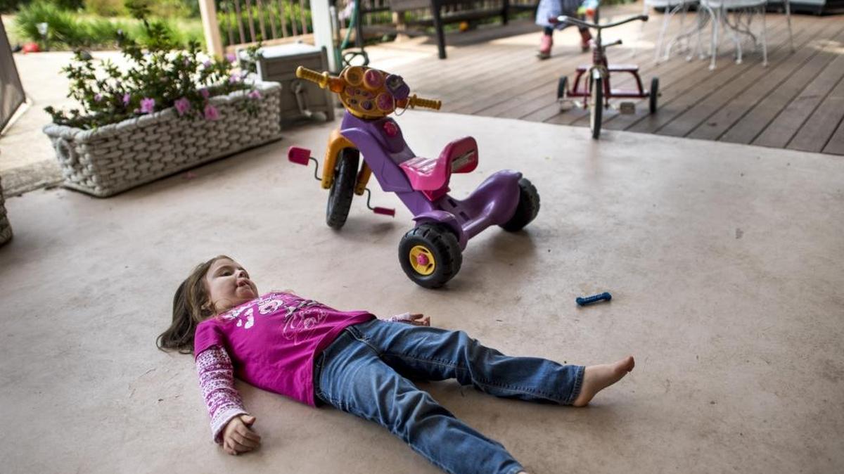 Brontë, 4, lies on her back as her sister Bridget, 3, runs around in the background Friday in Fair Oaks. The girls’ mother, Erin Byerly, a parenting blogger, says there’s an expectation in modern-day America for parents to keep their children ultra-clean.