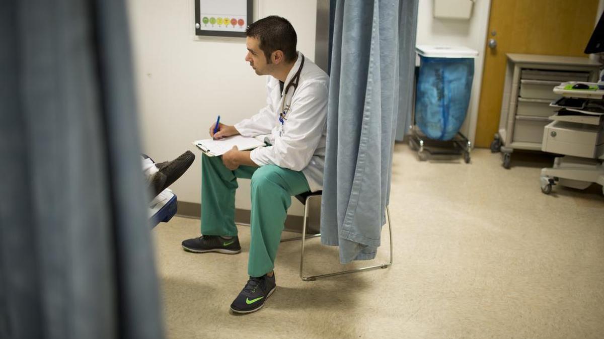 Dr. Michael Keller, director of Marion General's emergency department, speaks with a patient in the emergency room of the hospital in Marion, Ind., in 2016. The hospital issued tough opioid prescription guidelines two years ago, and its emergency room doctors cut opioid prescriptions nearly in half, but it's pain satisfaction scores from patient surveys dropped in response.