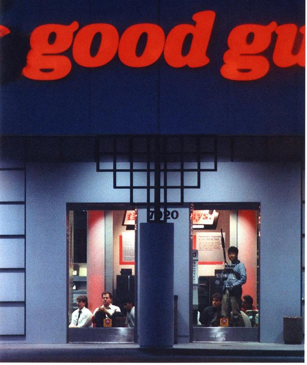 A gunman stands above bound hostages who are sitting on the floor at the Good Guys electronics store on April 4, 1991. The 8 1/2 hour siege ended when deputies stormed the store, leaving six dead, including three hostages. 