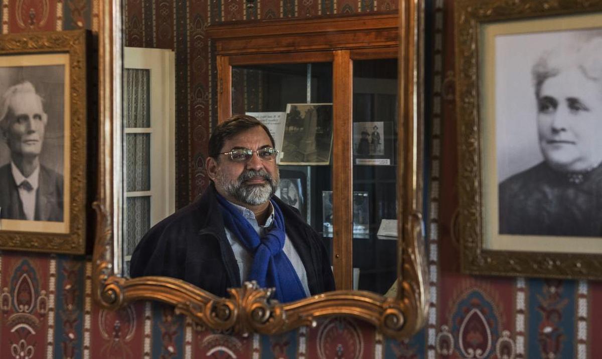 James Glica-Hernandez , executive director of the Gibson House, a historic home museum in Woodland stands in front of a mirror next to portraits of the original owners of the house William Byas Gibson and his wife Mary Isabell Cook on Thursday, February 1, 2018.