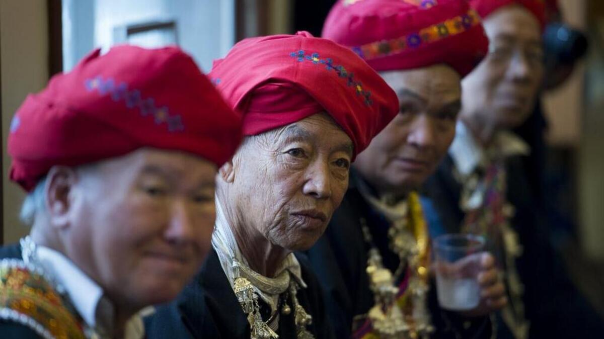Fou Saechao, Loung Guen Saechao, Yao Fon Saeteurn and Yao Liem Sautern watch Nai Saechao display a traditional Iu-Mien wedding dress at Parkview Presbyterian Church on Sunday Oct. 30, 2016, in Sacramento, Calif. Iu-Mien Community Services presented a cultural exhibit showcasing the history of Iu-Mien embroidery artwork.
