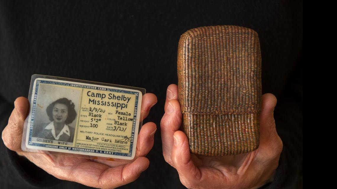 
Barbara Takei holds her mother’s cigarette holder made from string and her mother’s military ID.
