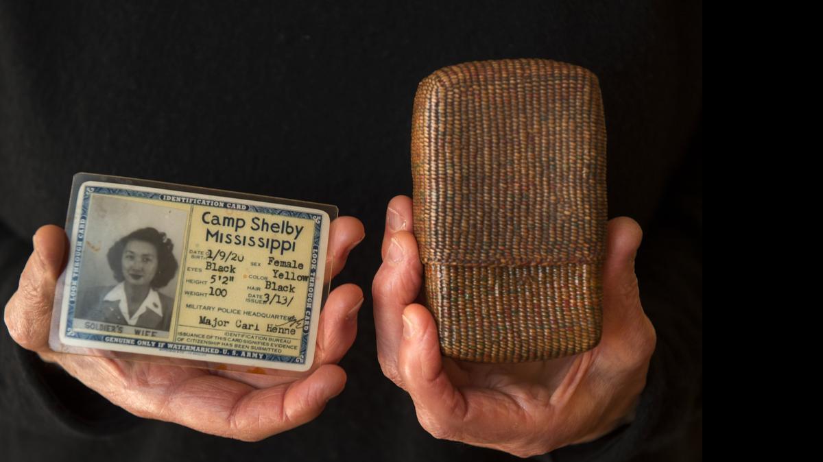 
Barbara Takei holds her mother’s cigarette holder made from string and her mother’s military ID.
