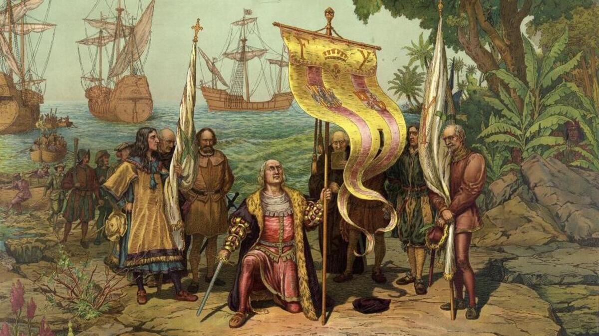 Christopher Columbus kneeling, holding a flag and sword with two other men holding flags upon arriving to America. There are other men on land and in boats behind Columbus and three ships in background.