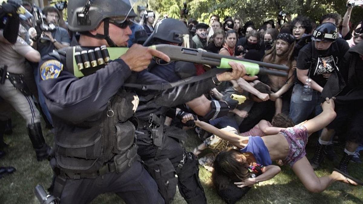 A female protestor is yanked by CHP officers in riot gear while her fellow protestors try to pull her away during a tense moment after a rally against the agriculture and technology conference in Sacramento on June 23, 2003. The CHP officers let the woman go and retreated from the lawn of the Capitol to N Street.