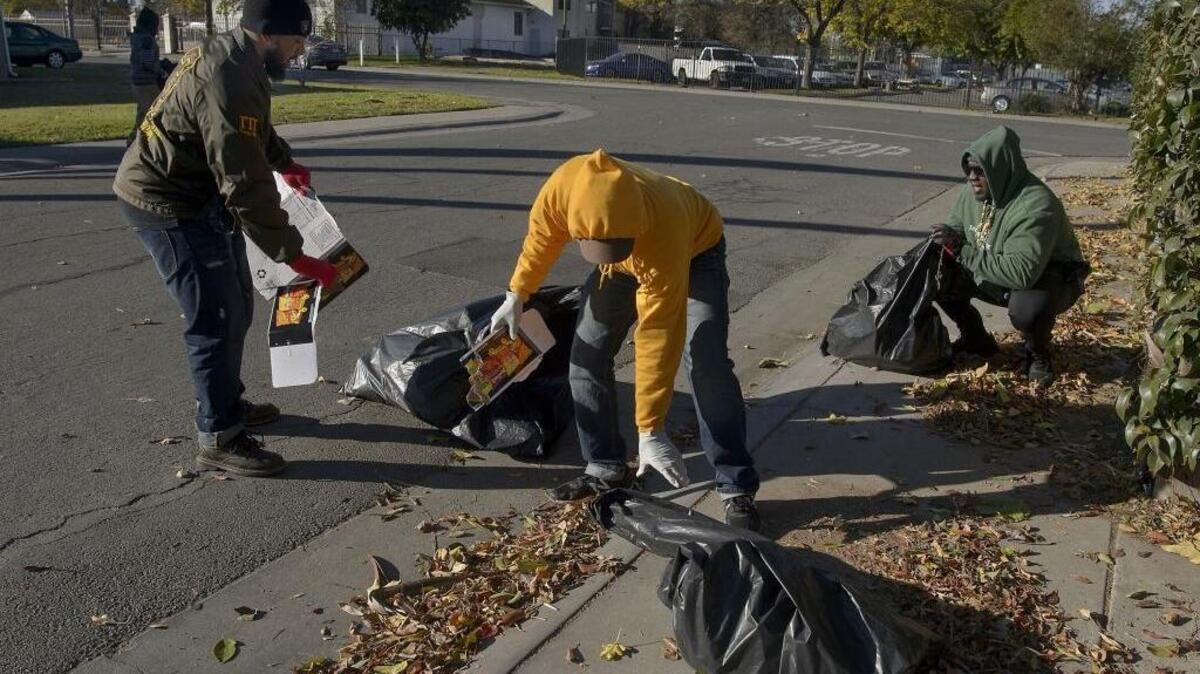 Volunteers Chris Perry, left, Jermaine Wilson and Marque Willis join dozens of other volunteers, mostly from Calvary Christian Center, to pick up trash and debris from the streets in north Sacramento on Saturday, December 16, 2017.