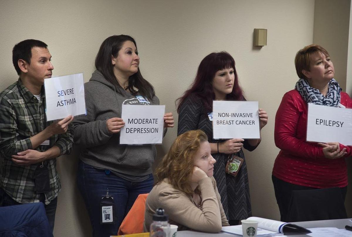 Library staff members from throughout the City of Sacramento hold placards, each listing a potential ailment, during an exercise about identifying and dealing with mental health issues, on Jan. 26, 2017.