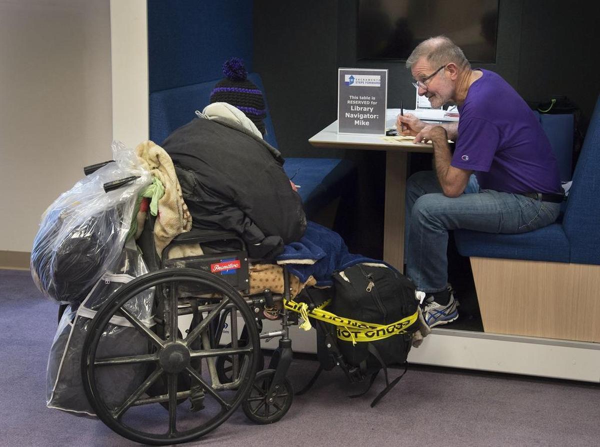 Library Navigator Mike Degner helps a homeless woman work through issues at the downtown library on Jan 26, 2017.