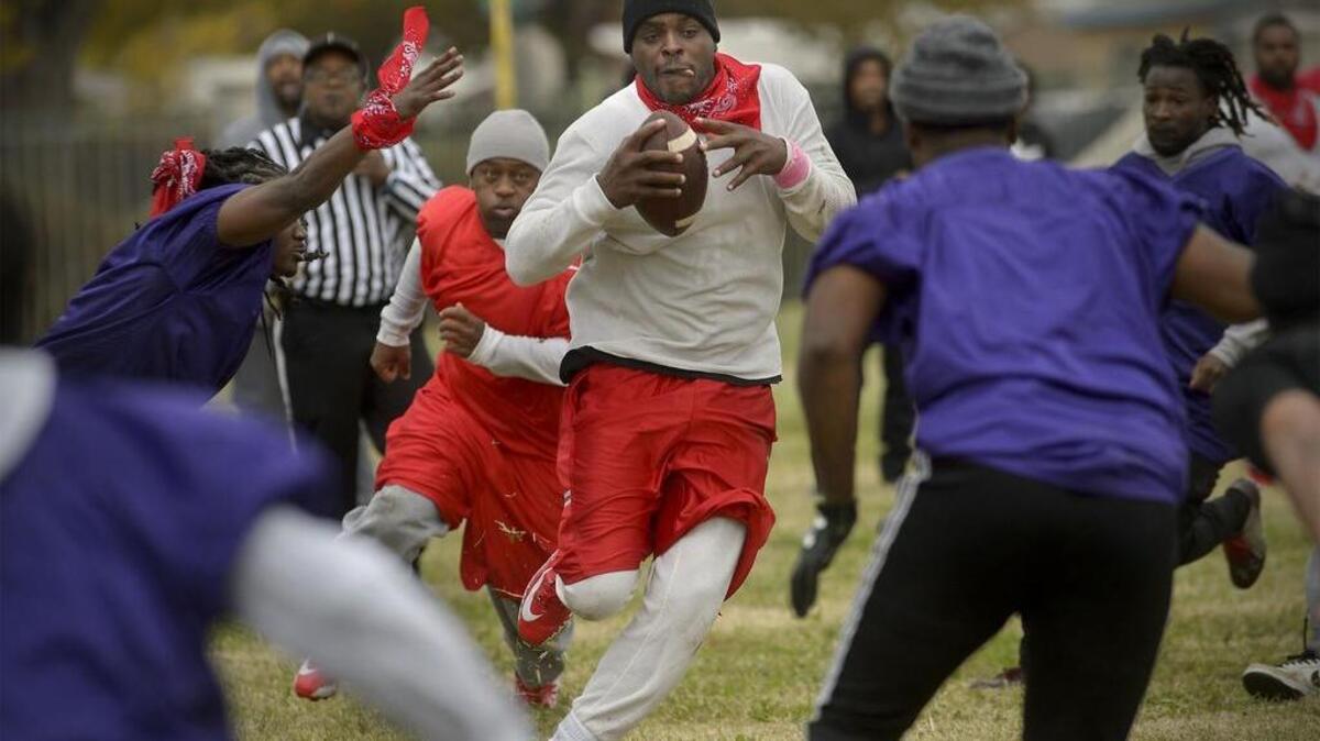 Grant High alumnus Damon Durrough, center, carries the ball for the “Old Guys” during the annual Turkey Bowl football game at the school on Thursday.