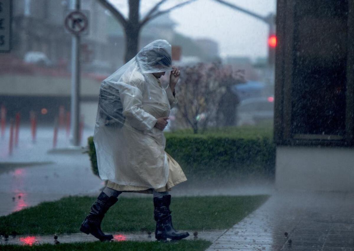 A pedestrian gets off the bus at the 7th and Capitol Bus stop prepared as rain and thunder hit the Sacramento area on Friday, March 4, 2016.