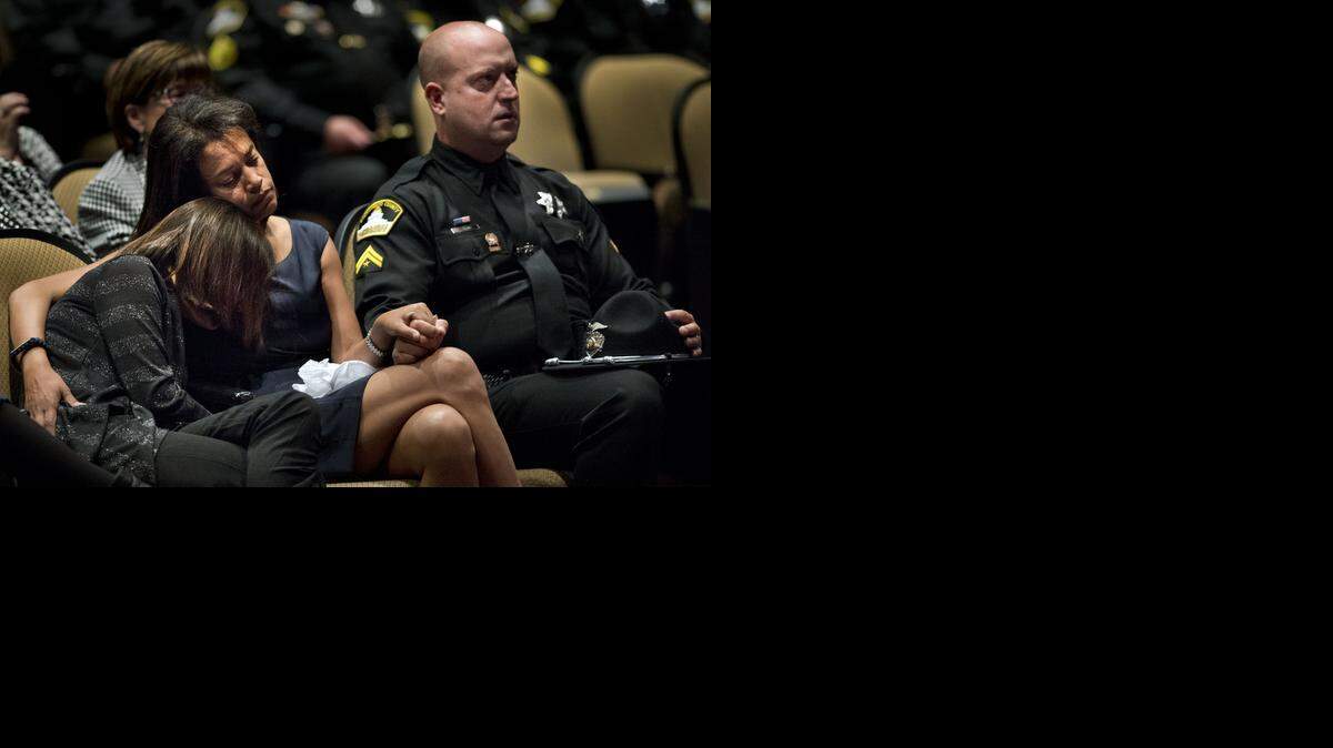 
Susan Oliver, wife of Sacramento County Sheriff's Deputy Danny Oliver, embraces her daughter Jenny Oliver, 11, and holds the hand of her husband's partner during a memorial service at Adventure Christian Church on Nov. 3, 2014 in Roseville, Calif. Deputy Oliver was one of two officers killed in an Oct. 24 rampage through Sacramento and Placer counties.

