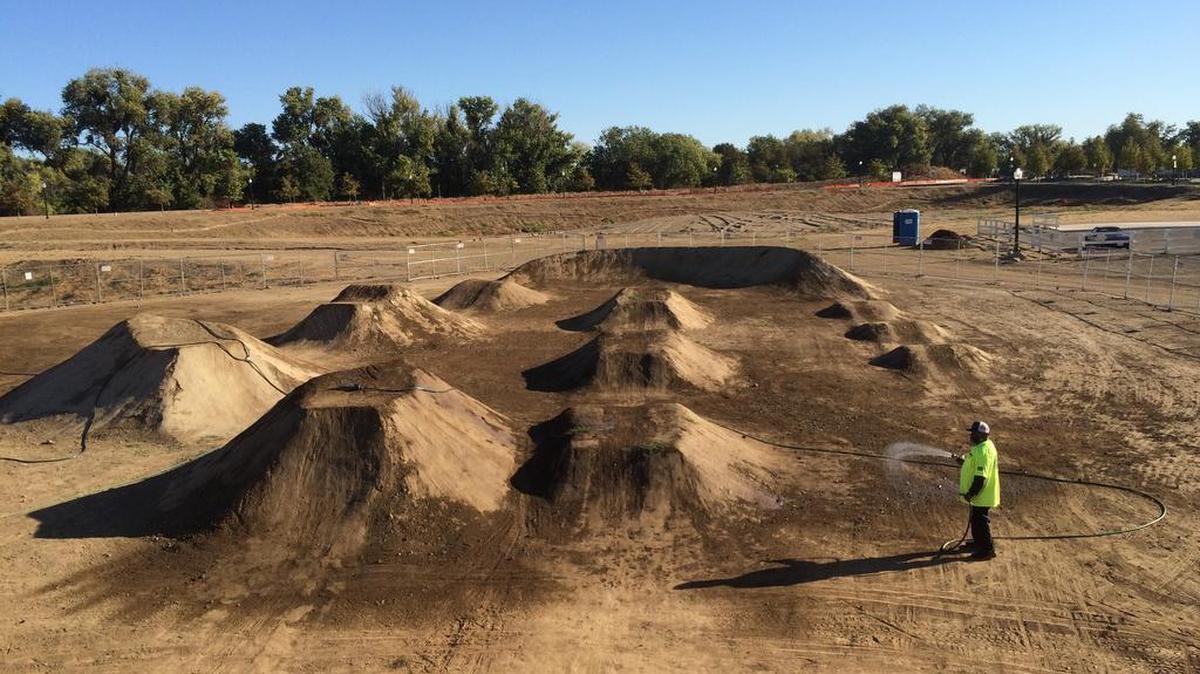 A worker waters down the jumping area at the new off road bike park set to open on Saturday.