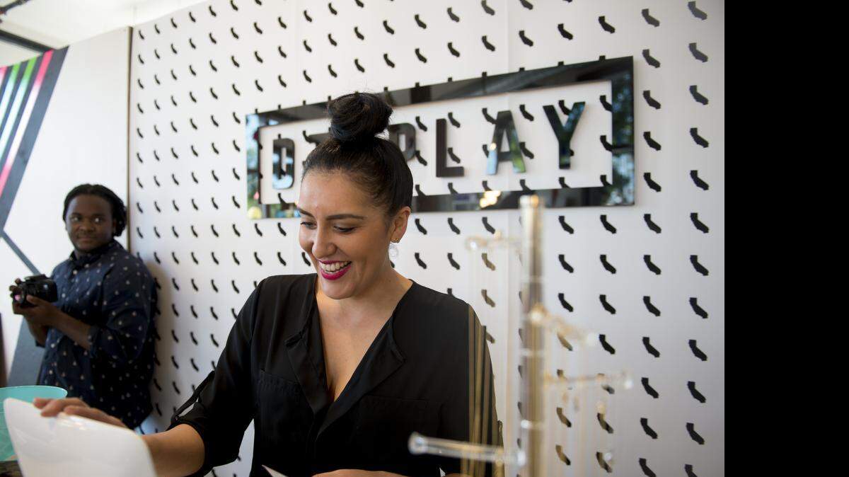 
Maritza Davis helps a customer while her husband, Roshaun Davis, left, takes video at their pop-up shop in early April in Sacramento.
