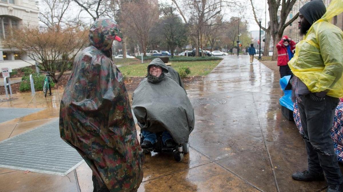 Russell Rawlings, center, who is running for Sacramento mayor, rolls up in his wheelchair outside of City Hall to talk with homeless rights advocates who have been camping there, Monday, Dec. 21, 2015.
