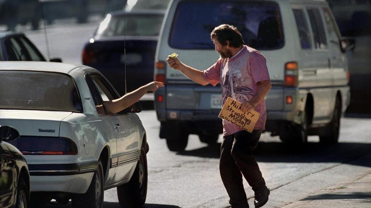 David “Doc” Walker secures money from a passing car while flying a sign that says “Hungry Struggling Model” near the corner of Howe Ave and Fair Oaks Blvd July 26, 2001.
