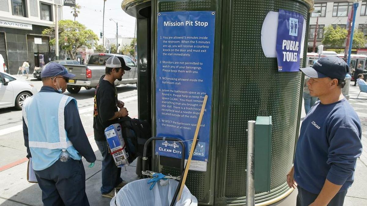 An attendant looks on as a man enters a Pit Stop public toilet outside a Mission District transit station in San Francisco on July 30, 2015.