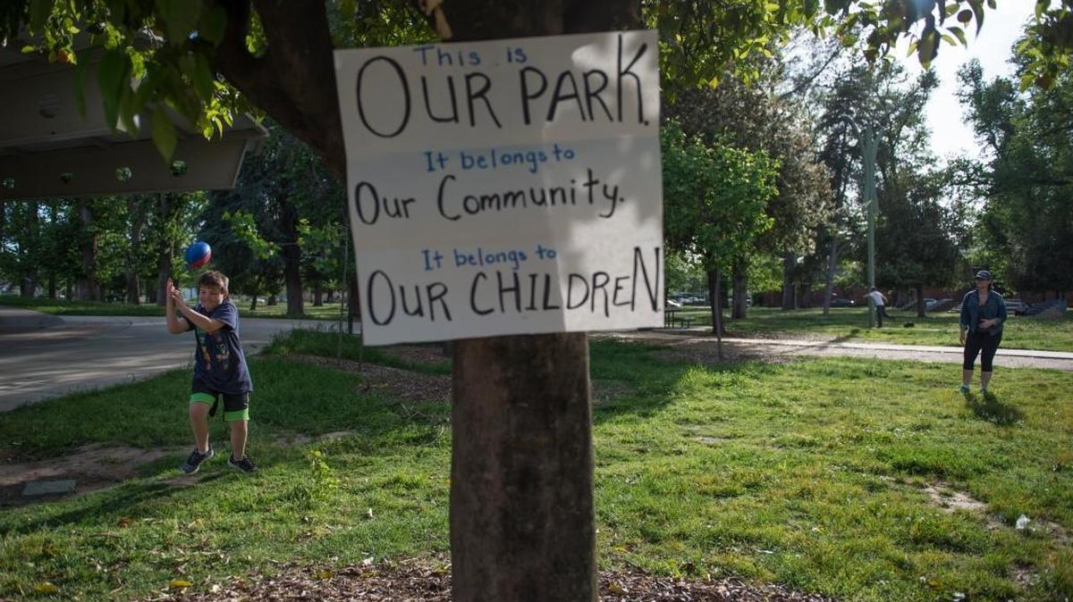 Kirsten Spall and her son Robert Spore play catch in McClatchy Park while her fellow community members rally April 13 for improved safety in Oak Park following a shooting the previous night.