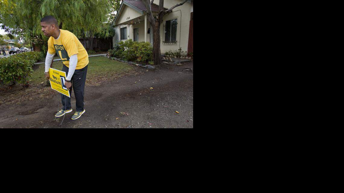 
Sacramento Mayor Kevin Johnson installs a lawn sign while campaigning door-to-door for Measure L in Sacramento on Saturday.
