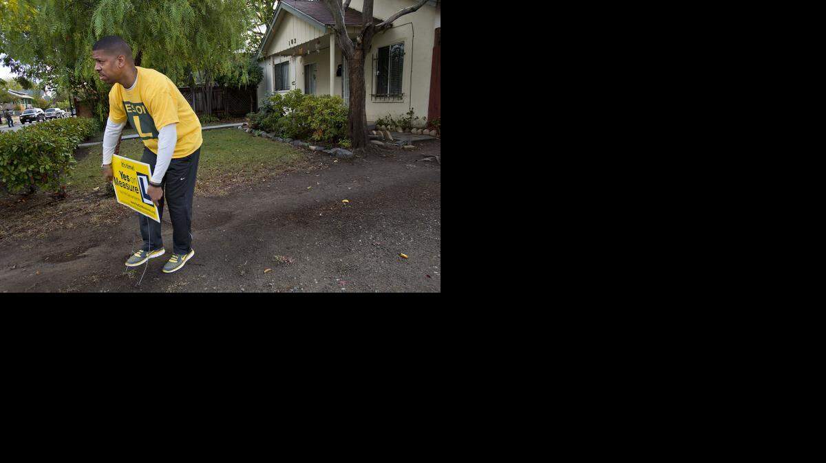 
Sacramento Mayor Kevin Johnson installs a lawn sign while campaigning door-to-door for Measure L in Sacramento on Saturday.
