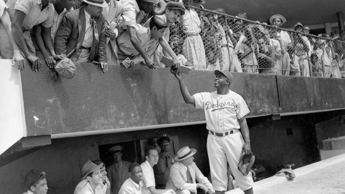 Jackie Robinson of the Brooklyn Dodgers returns an autograph book to a fan on March 6, 1948, during the Dodgers’ spring training in the Dominican Republic. This week is the 69th anniversary of his debut in the major leagues.