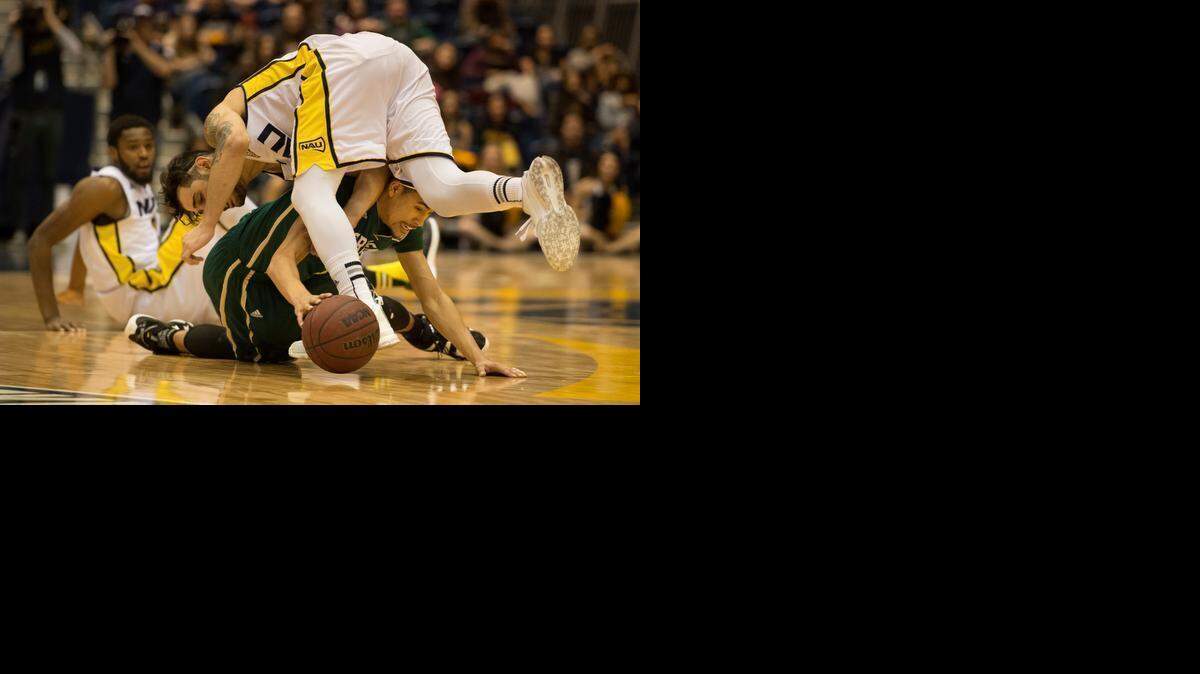 
Sac State Hornets guard Mikh McKinney (10) tries to maintain ball possession as Northern Arizona Lumberjacks guard Kris Yanku (4) falls over him in the second half on Saturday, March 7, 2015, at Walkup Skydome in Flagstaff, Ariz.
