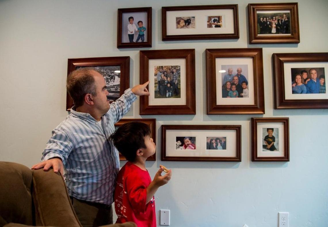 Dan Okenfuss points out members of the family to his son Hai at their home in Land Park.
