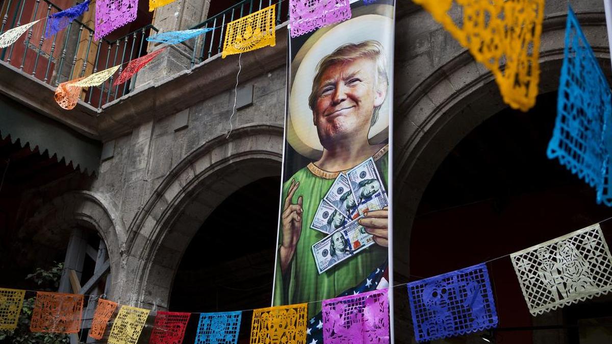 In this Nov. 10, 2016 file photo, a banner with an image of Donald Trump promotes an exhibition titled; "Trump: A wall of caricatures," surrounded intricately-cut tissue paper known as papel picado, inside the Caricature Museum in downtown Mexico City.