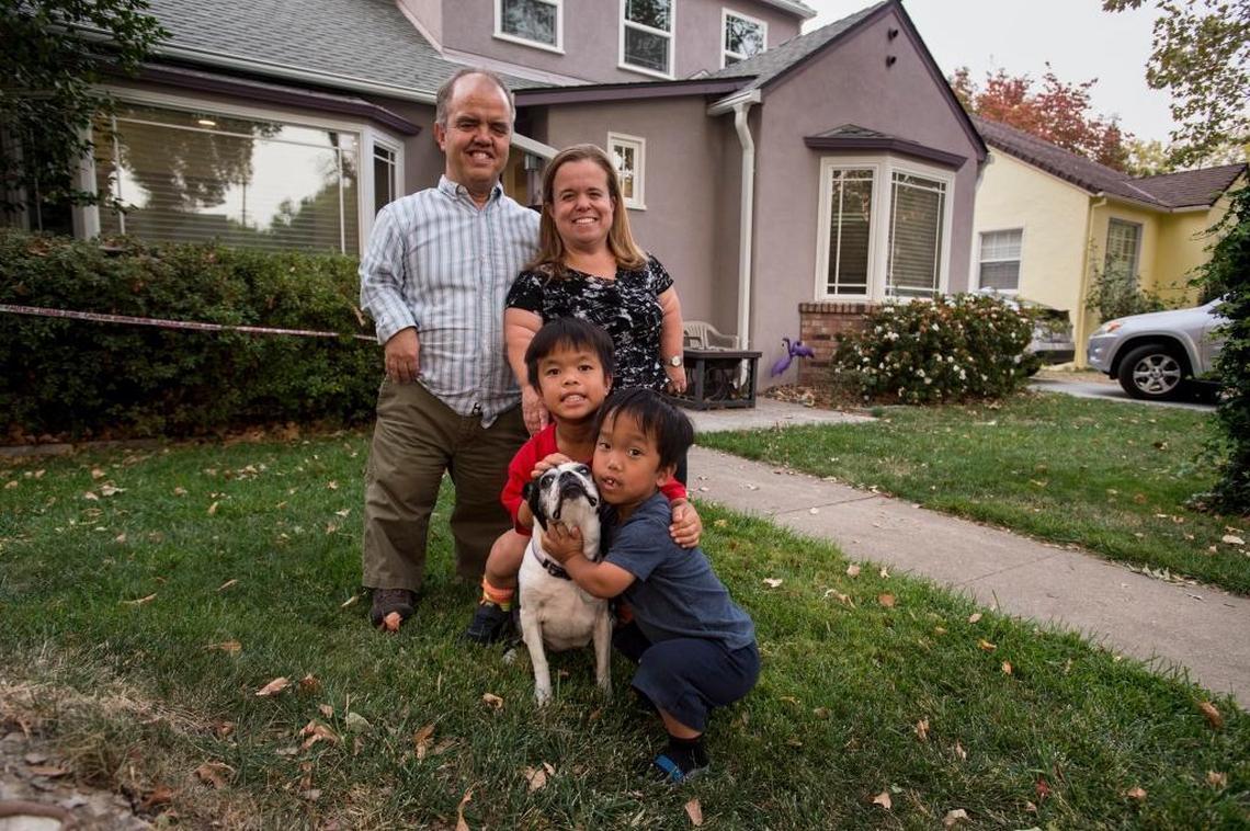 Dan and Ericka Okenfuss with their sons Hai and Jude and their dog Scout outside their home in Land Park.