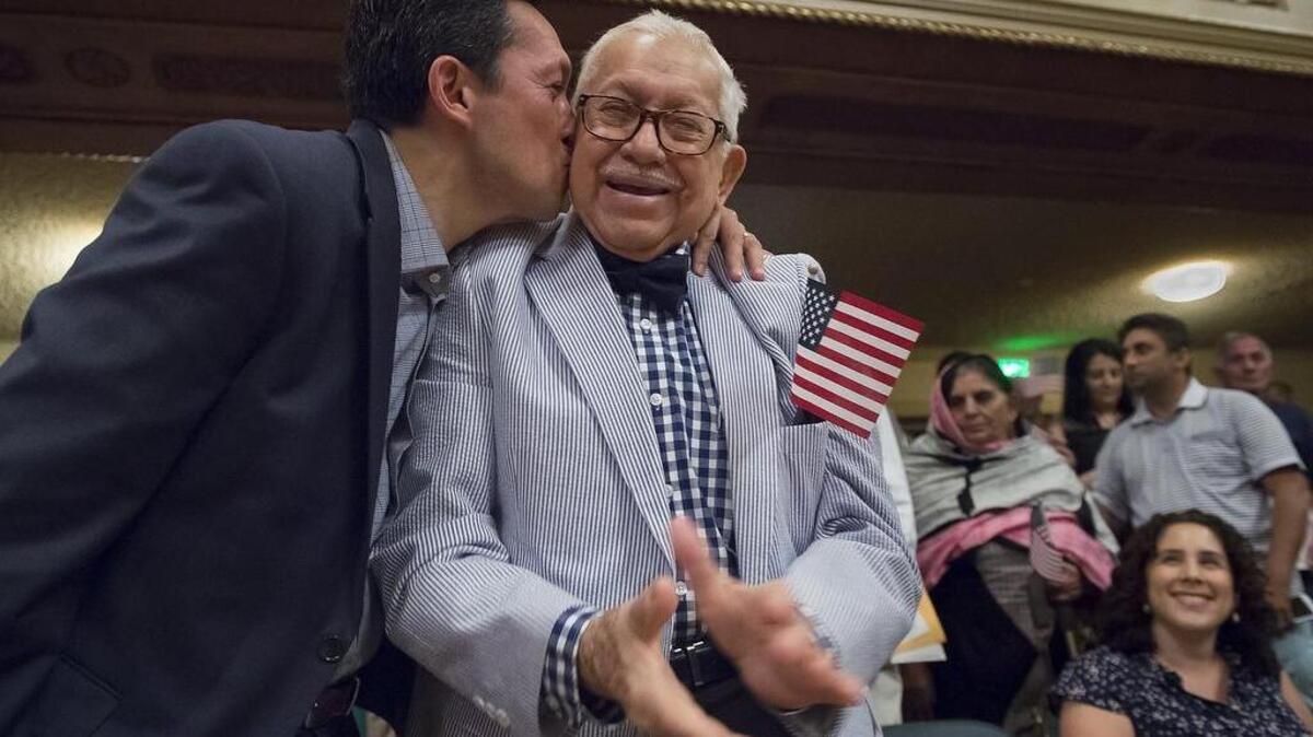 After Wednesday’s citizenship ceremony, Washington Espinoza, right, filled out a voter registration card with help from his son Pablo and alongside his grandson Adrian, 18, left, who also will vote in his first election in November.