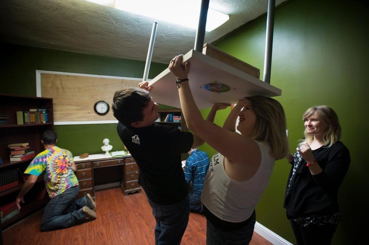 Chris Sandoval, 25, and Megan Lowry, 24, hold up a table and search for clues as Phoebe Smith, right, watches during opening night for Escape Sacramento in October 2015. Sacramento escape room Enchambered was named one of the top 10 escape rooms in the United States by USA Today.