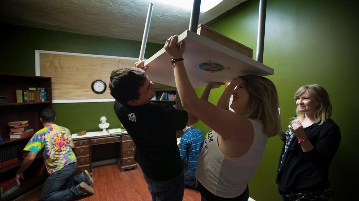 Chris Sandoval, 25, and Megan Lowry, 24, hold up a table and search for clues as Phoebe Smith, right, watches at Escape Sacramento. A different local escape room, Enchambered, was named No. 1 in the nation by USA Today readers.