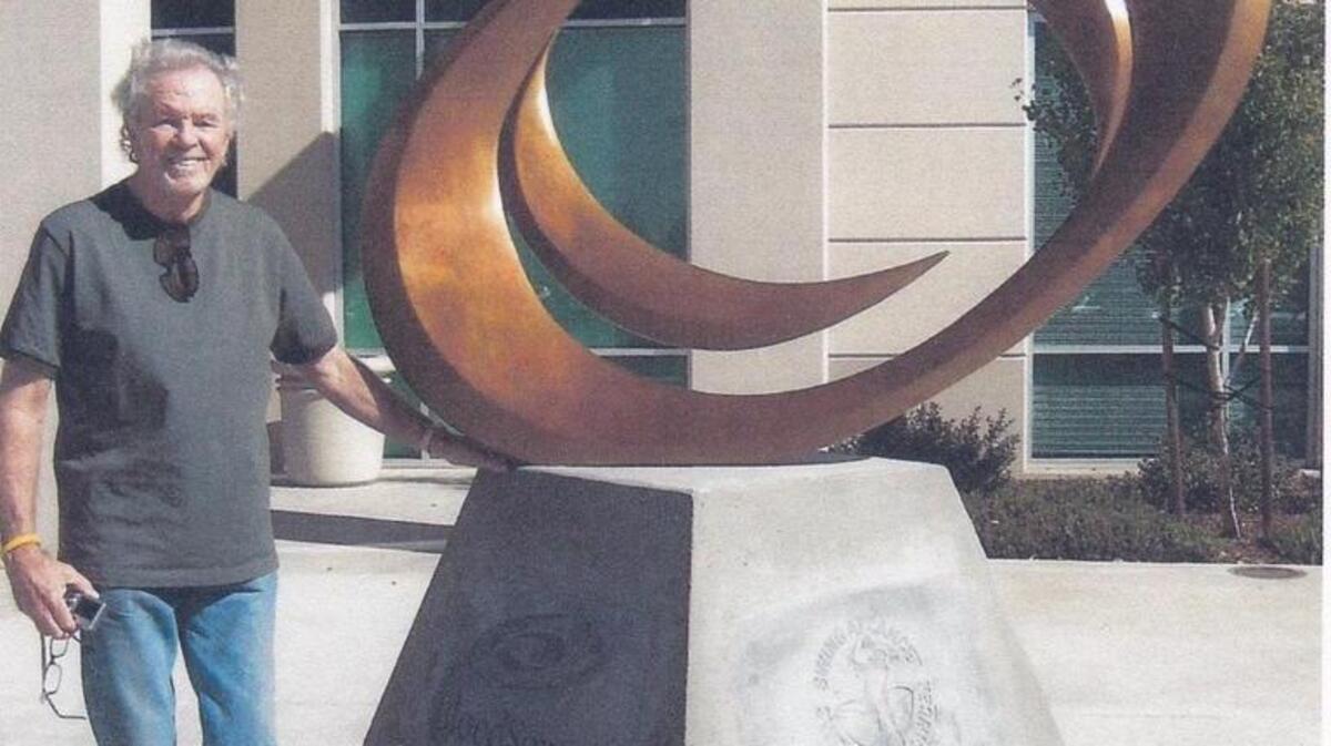Tom Bennett poses with an 8 foot sculpture he created for the BloodSource building near Sacramento