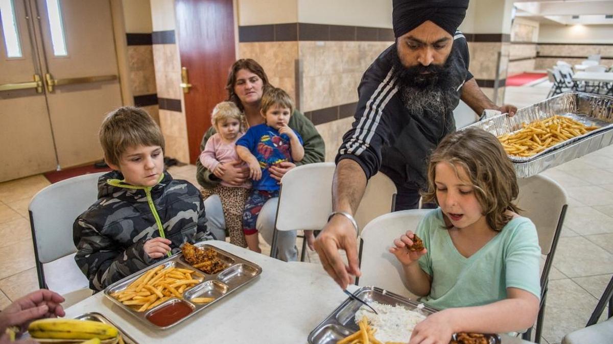 Amarjit Singh, second from right, helps serve french fries to members of the Lyon family from Yuba City at the Gurdwara Sahib Sikh Temple Sacramento on Monday, Feb,13, 2017 in West Sacramento. The family including son Brian, 8, at left, mom Roxanna,32, center, holding Laurie, 2, and Wyatt, 3, and daughter Trinity, 9, right, said they had not eaten since 4 p.m. Sunday. The temple – the area's oldest and largest, took in more than 200 people last night and this morning who were forced to evacuate the towns between Wheatland and Oroville.