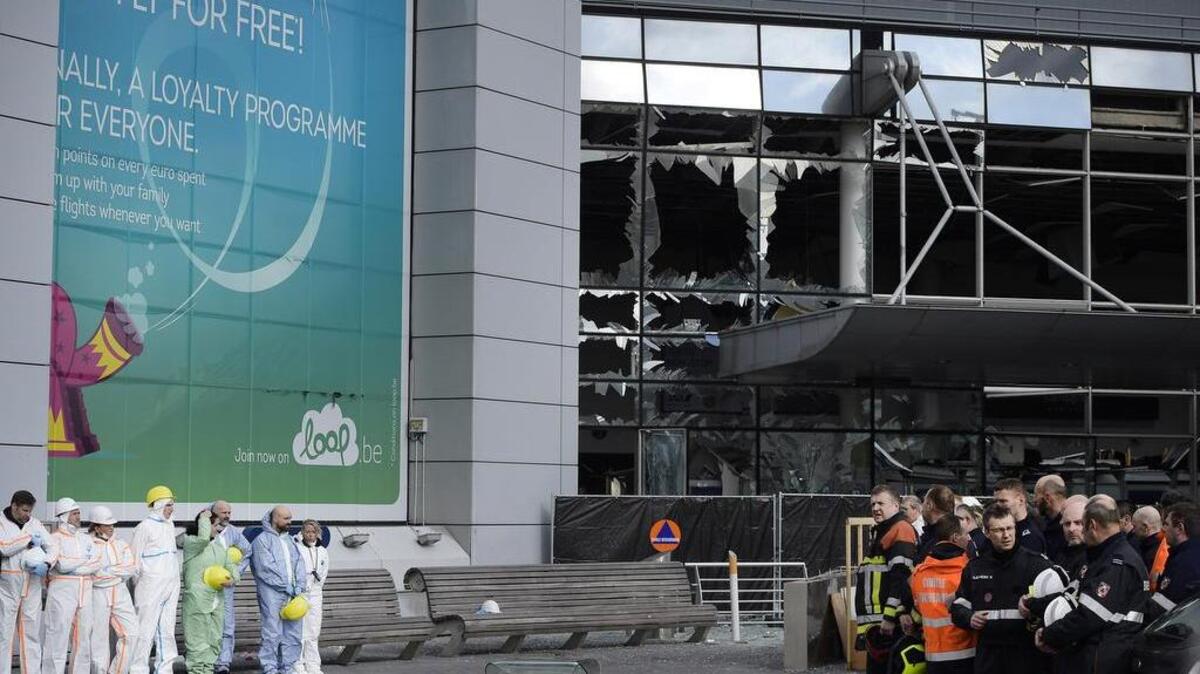 Forensic officers and firemen stand in front of the damaged terminal at Zaventem Airport in Brussels on Wednesday, March 23, 2016.