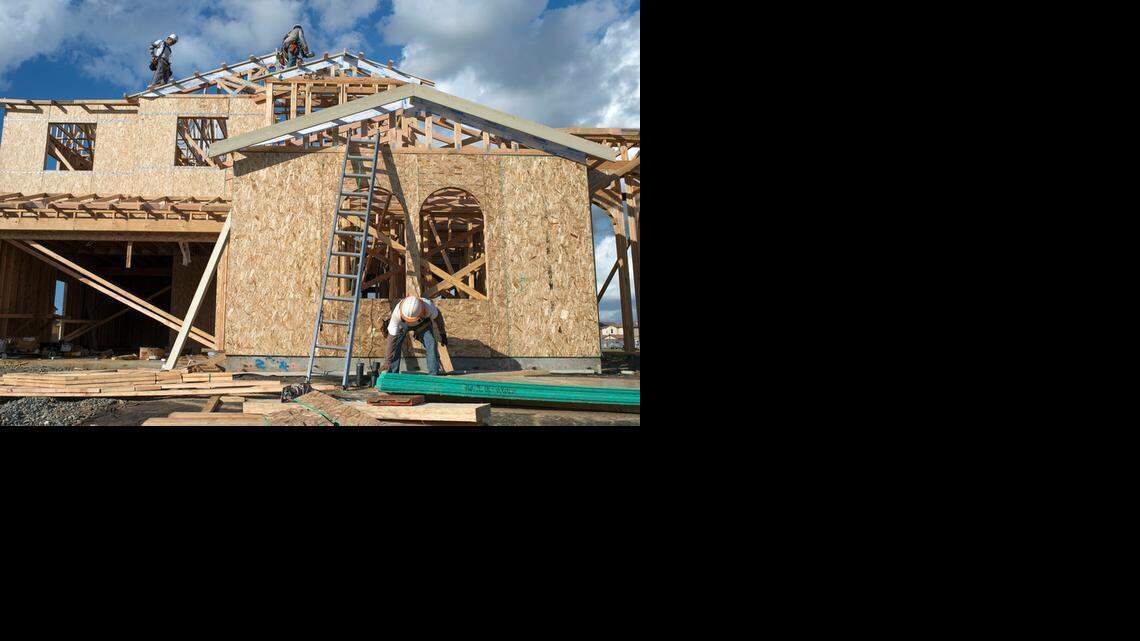 
Miguel Villa of Elk Grove, bottom right, cuts wood as his crew builds a new home Monday in Elk Grove. The sounds of nail guns, hammers and saws are returning as more building permits are issued for the area.
