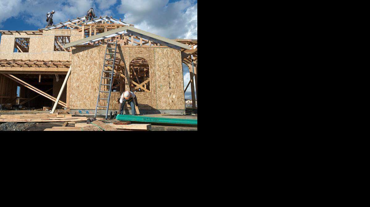 
Miguel Villa of Elk Grove, bottom right, cuts wood as his crew builds a new home Monday in Elk Grove. The sounds of nail guns, hammers and saws are returning as more building permits are issued for the area.
