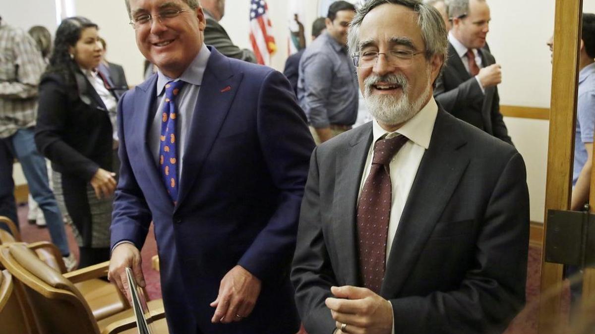 City Attorney Dennis Herrera, left, smiles while walking with San Francisco Supervisor Aaron Peskin, right, after announcing a settlement agreement on short-term rentals during a news conference Monday at City Hall in San Francisco. San Francisco and Airbnb have reached a deal to end a lawsuit over a law that fines the company for booking rentals not registered with the city.