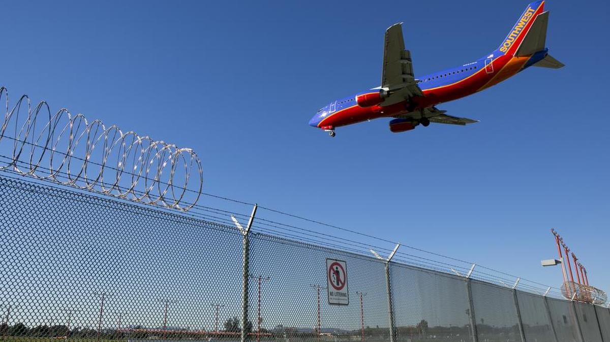 AP FILE -- In this Friday, Jan. 23, 2015 photo, a passenger jet flies over the perimeter fence at the Los Angeles International Airport.