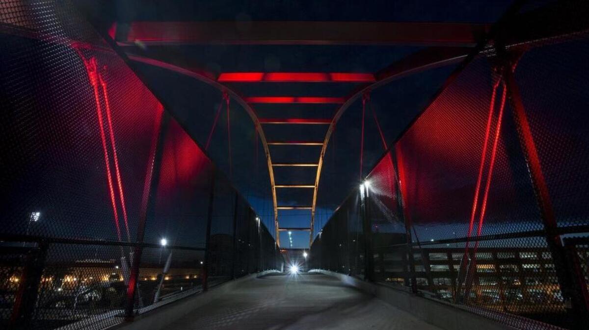 The pedestrian bridge between Crocker Village in Curtis Park and Sacramento City College is lit red and gold on Thursday night in a display created by Sacramento city engineer Sompol Chatusripitak.
