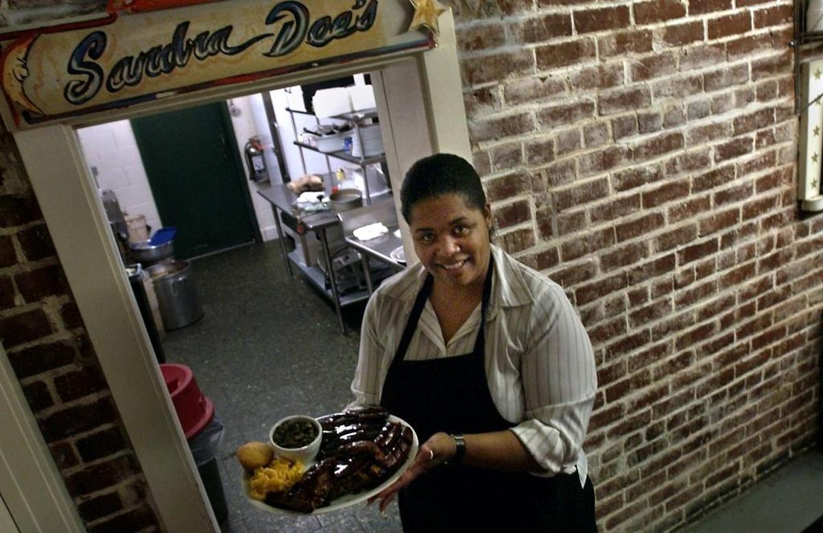 Sandra Dee Johnson stands outside her kitchen at the restaurant bearing her name, Sandra Dee's Bar-B-Que & Seafood, at the corner of 15th and F streets.
