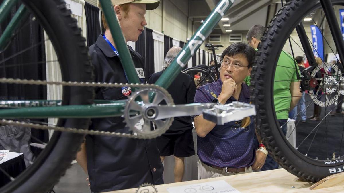 Loren Sunding of Auburn, talks to Peter shin of Stockton, about the bike Sunding helped build for the Cal Poly San Luis Obispo Bike building club, during the North American Handmade Bike Show at the Sacramento Convention Center, Saturday Feb 27, 2016.
