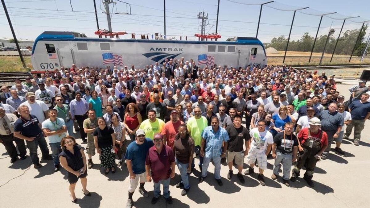 Siemens employees with Amtrak, state and federal officials officials in front an electric locomotive at the Siemens’ rail manufacturing hub in Sacramento.