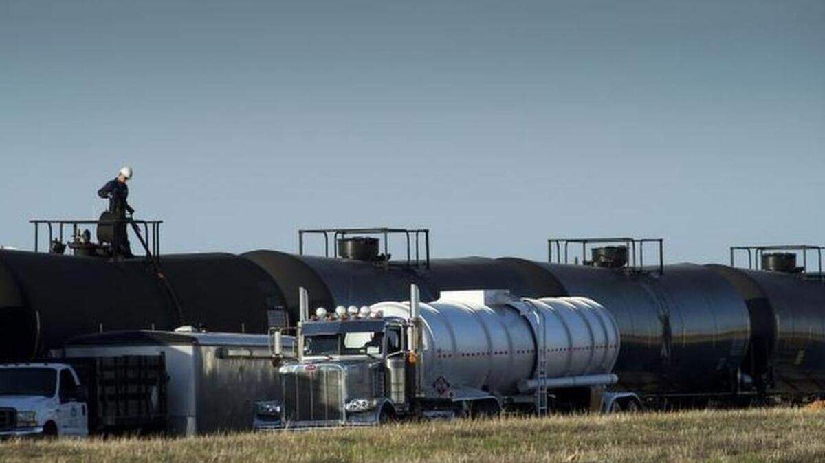A tanker truck is filled from railway cars containing crude oil at McClellan Park in 2014.