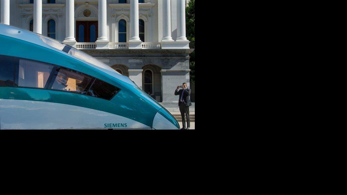 
A passer-by photographs the front of a model high-speed train on the west steps of the state Capitol in Sacramento on Tuesday. 
