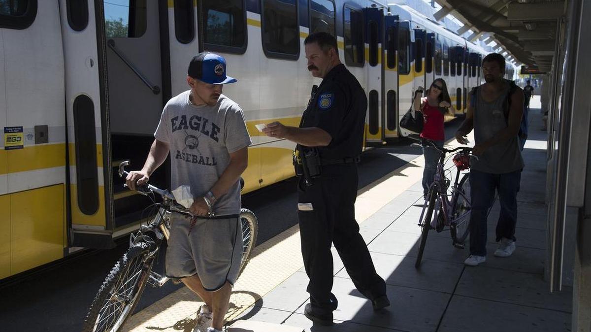 A Regional Transit police officer checks the ticket of a rider near a train at the Watt/ I-80 station on Monday, July 31, 2017 in Sacramento, Calif. Sacramento's light rail operator has installed 14 surveillance cameras and made other safety improvements at the North Highlands station where a deputy was shot in the face last month during a scuffle on the station platform.