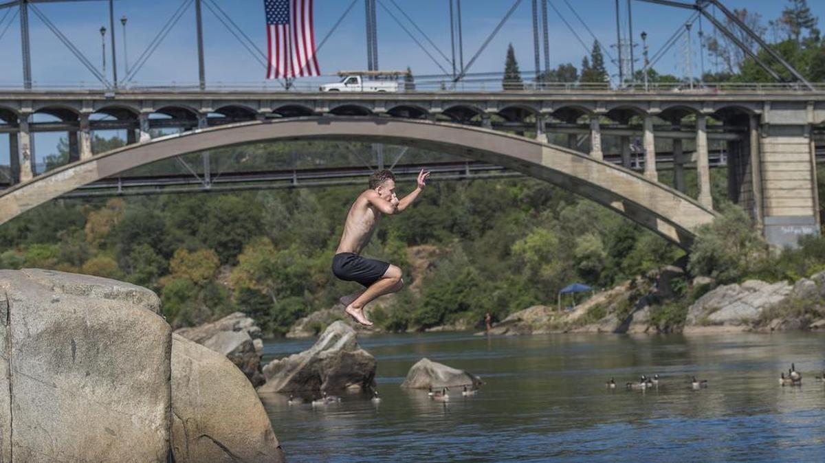 Alan Volkov, 15, of Rancho Cordova takes a jump into the ice cold Lake Natoma near the Rainbow Bridge in Folsom on Friday, June 3, 2016.