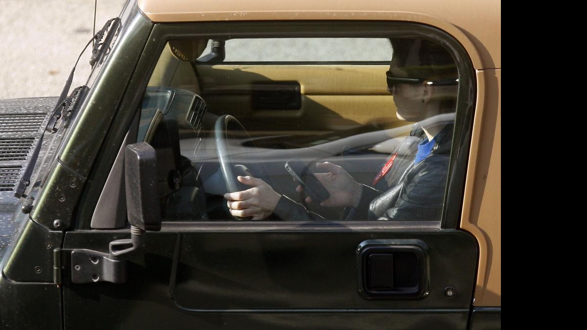 
A driver takes his eyes off the road to text behind the wheel. (AP Photo/Damian Dovarganes, File)
