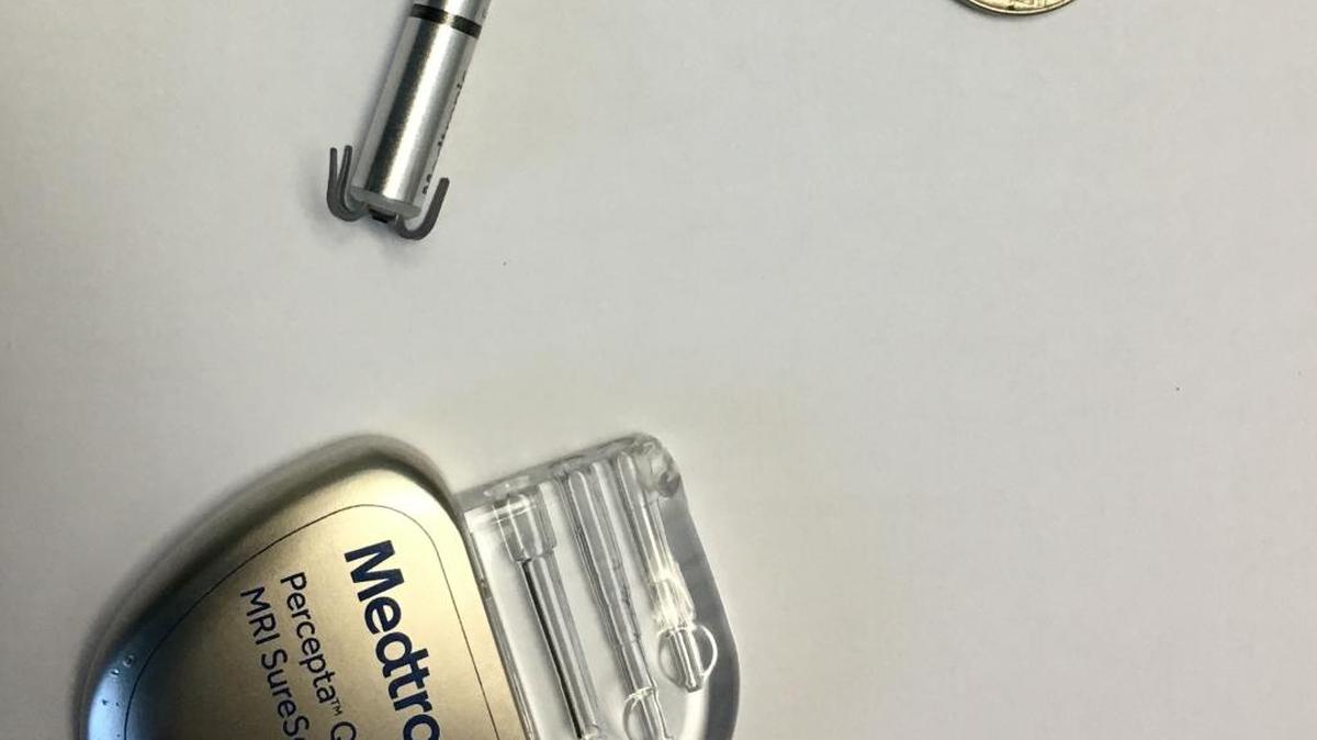 The traditional pacemaker, bottom, dwarfs the new Micra Transcatheter Pacing System and a nickel.